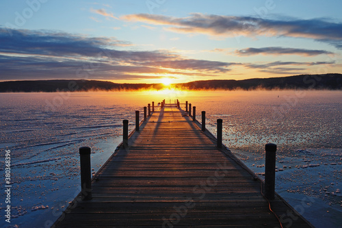 Symmetrical view of jetty on frozen lake, hills in background at sunrise photo