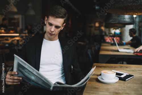 Serious businessman reading newspaper in cafe