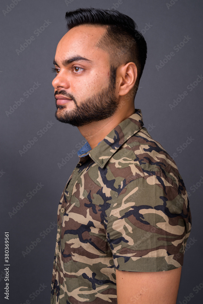 Young bearded Indian man against gray background Young bearded Indian man against gray background
