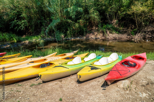 A set of ten old and worn kayak of various color.