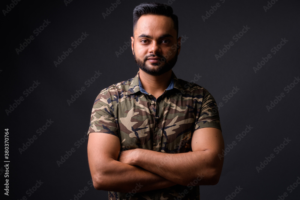 Young bearded Indian man against gray background Young bearded Indian man against gray background