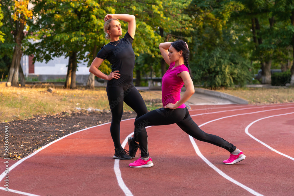 Obraz premium Two fit athletic girls posing on a sports track