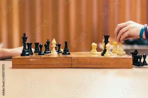 Hands playing chess on a wooden board photo