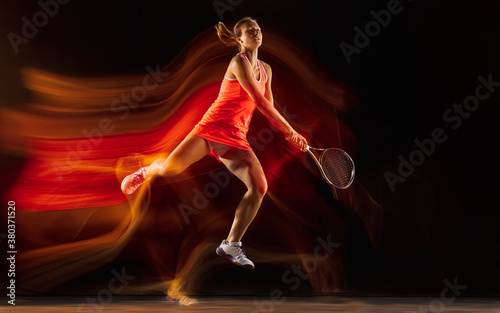 Competition. Professional female tennis player training isolated on black studio background in mixed light. Woman in sportsuit practicing. Healthy lifestyle, sport, workout, motion and action concept. © master1305