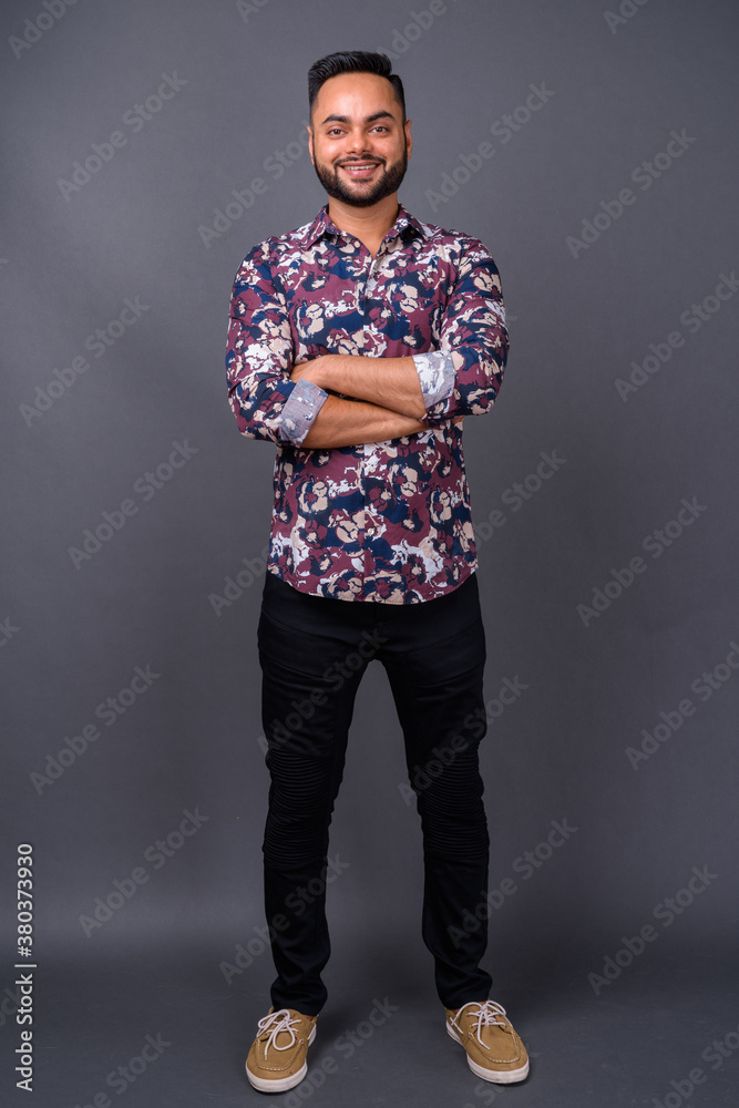 Young bearded Indian man against gray background Young bearded Indian man against gray background