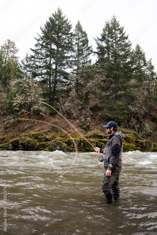 Man stands in the river casting an orange fly fishing line. Man stands in the river casting an orange fly fishing line.