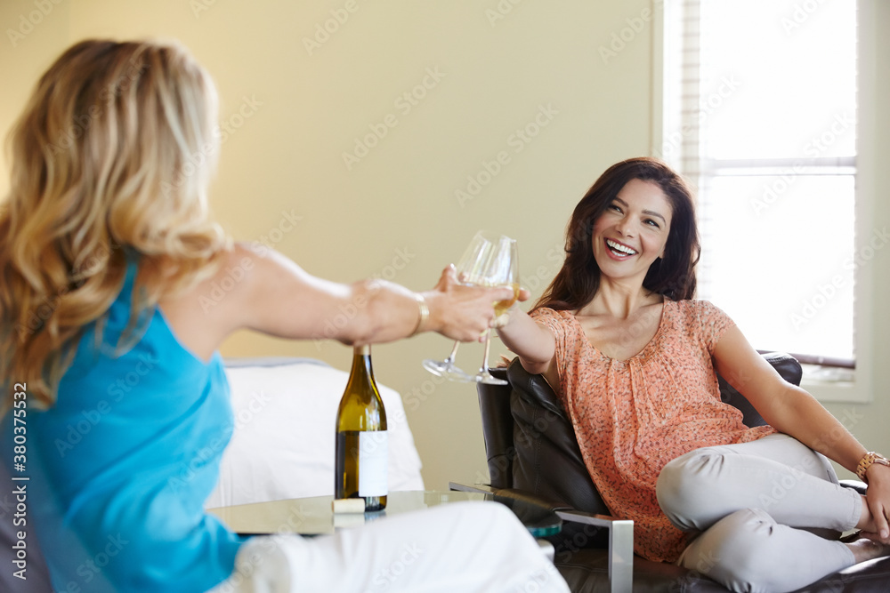 Girlfriends relaxing with wine in luxury hotel room.