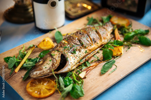 Roasted sea bass with herbs on the wooden board