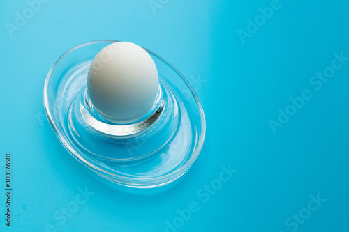 white chicken egg on a stand on a blue background.