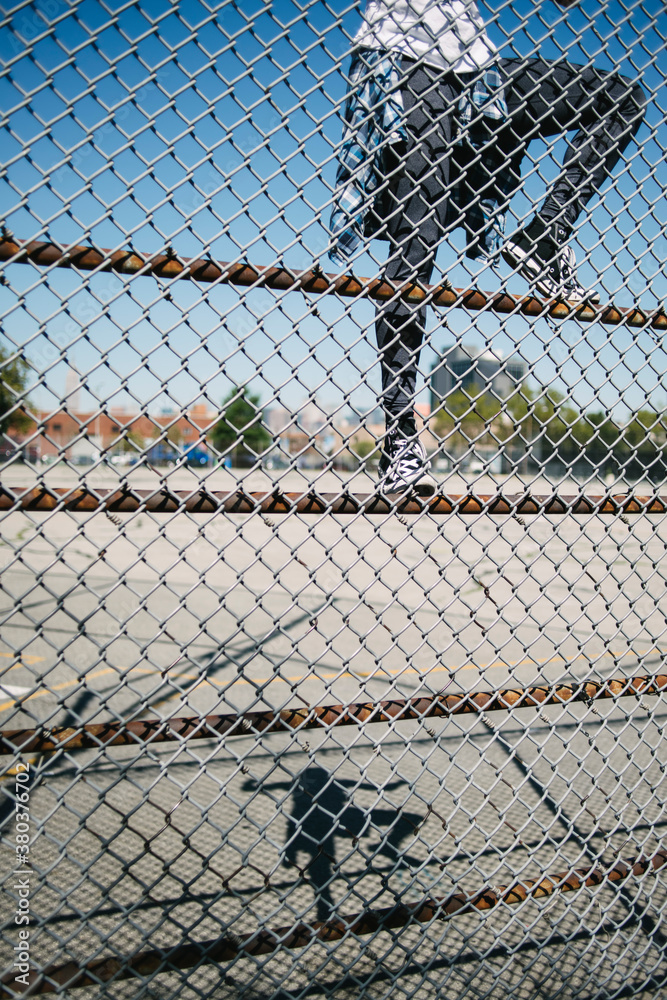 Young woman climbing the netting in urban area Young woman climbing the netting in urban area