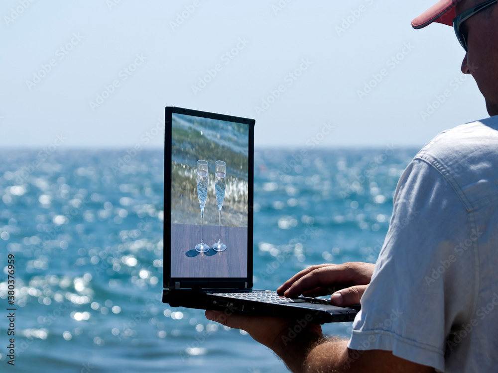 Man with laptop in front of sea