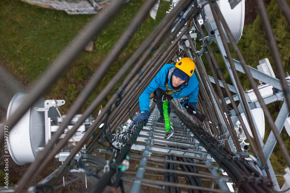 Working at heights, technician climbs up on a communications tower Working at heights, technician climbs up on a communications tower