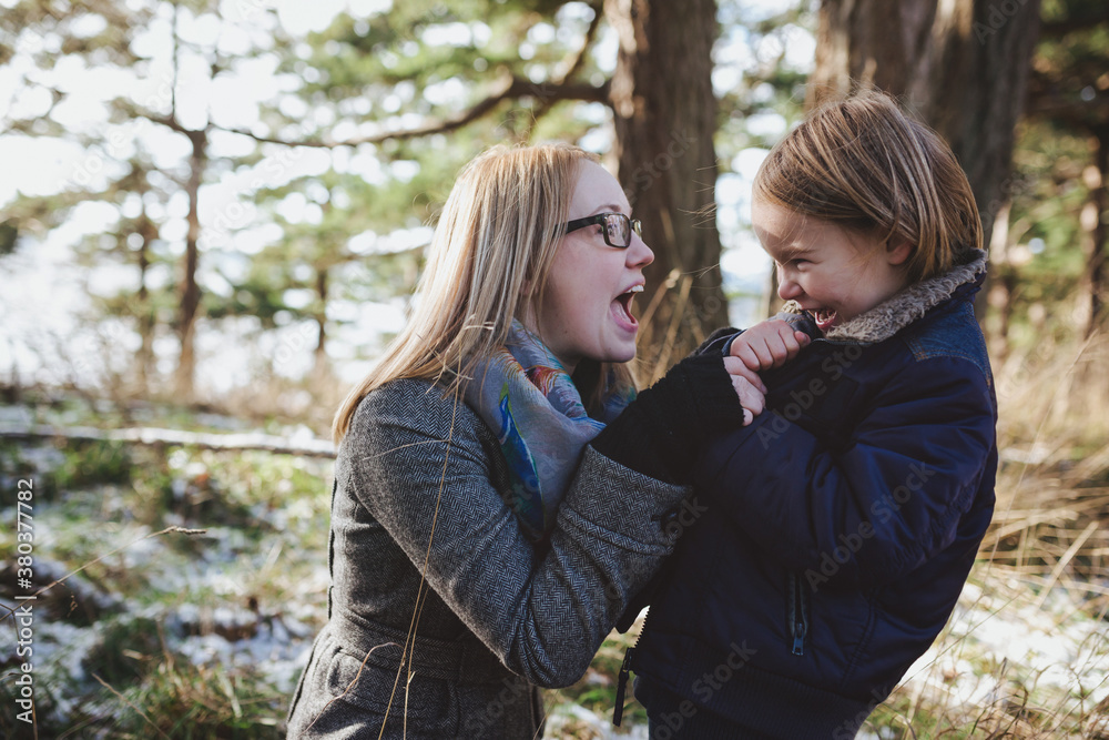 Young, pretty mom playing with cute son outside in winter - fun Young, pretty mom playing with cute son outside in winter - fun
