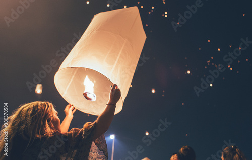 Festival time - Blonde woman releasing fire lantern into the night sky photo