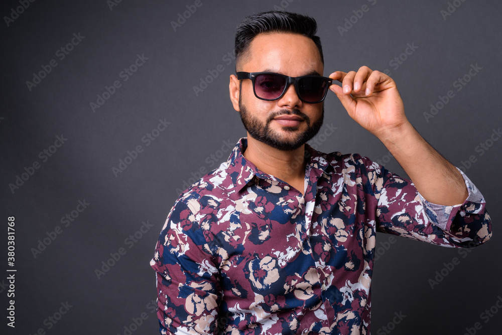 Obraz premium Young bearded Indian man against gray background