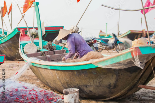 Fishermen repairing nets on a boat trip out to sea in the afternoon July 31, 2014 at the beach of Hai Ly, Vietnam. © binhdd