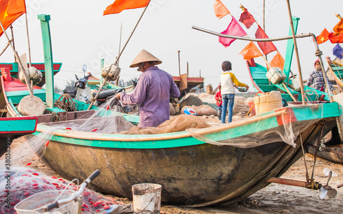 Fishermen repairing nets on a boat trip out to sea in the afternoon July 31, 2014 at the beach of Hai Ly, Vietnam. photo