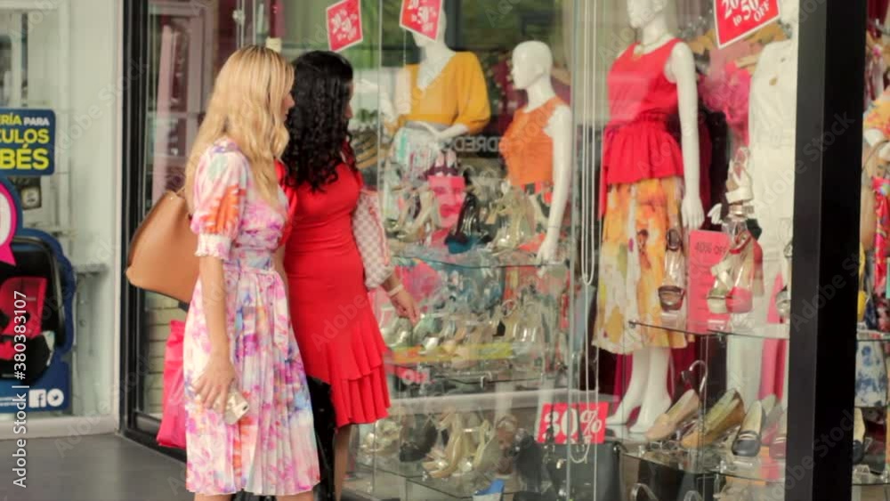 Amigas viendo ropa en aparador de tienda comercial