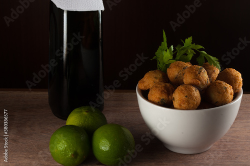 Salt cod fritters in a white bowl with fresh lemons and olive oil bottle. Selective focus