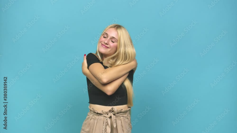 Young caucasian blonde woman hugs, smiling carefree and happy