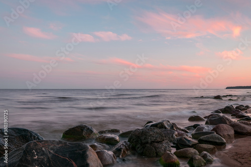 rocky sea shore before sunrise  dark stone silhouettes and colorful sky