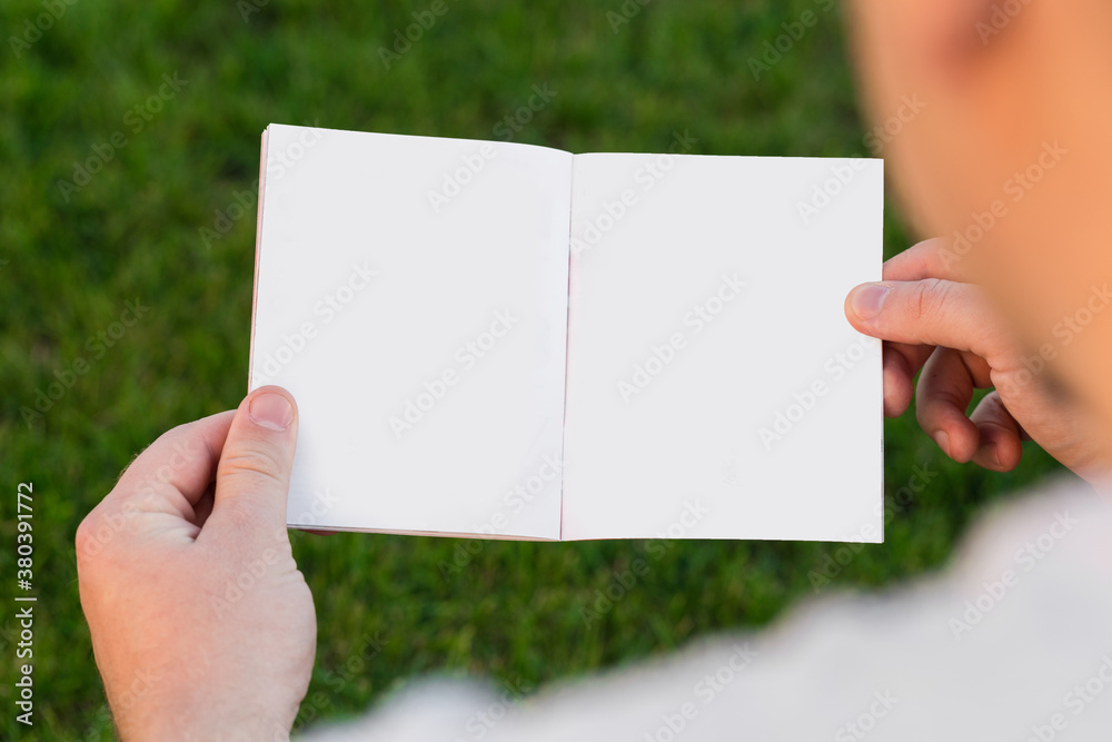 Layout of the cover of the magazine, catalog, book. a man reading a blank magazine, catalog, book sitting on a green lawn Layout of the cover of the magazine, catalog, book. a man reading a blank magazine, catalog, book sitting on a green lawn