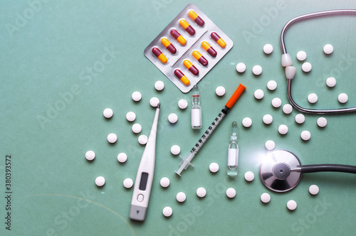 Pills, ampoule, syringes, capsules, stethoscope on the green doctor s table.