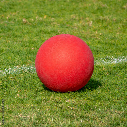 Photos Red Playground kickball ball on the green grass in the bright sunshine