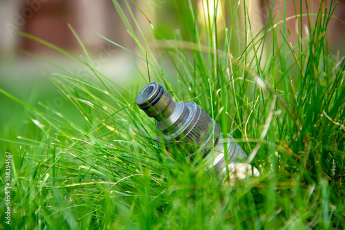 Metal lawn faucet installed on the ground in the grass, side view, selective focus, close-up. photo