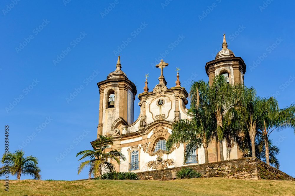 Ancient and historic church in 18th century colonial architecture on top of the hill in the city of Ouro Preto in Minas Gerais, Brazil with towers and palms