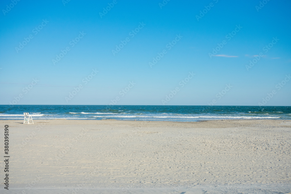 An Empty Beach With a Lifeguard Chair on a Clear Blue Sky