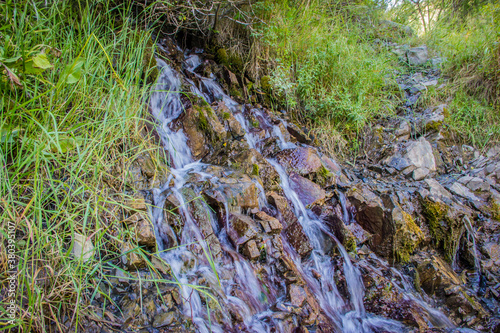 Small cascading waterfall from mountain stream at Kolsay lake in the Kazakhstan. Fresh stream in mountains.