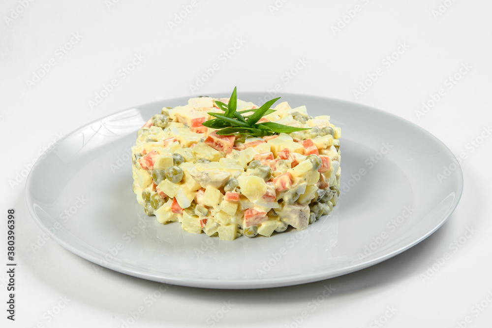 Traditional Russian salad Olivier served with spring onion scallions in culinary ring on serving plate isolated on light background. Vegetable and meat Ukrainian salad. Winter Christmas salad Traditional Russian salad Olivier served with spring onion scallions in culinary ring on serving plate isolated on light background. Vegetable and meat Ukrainian salad. Winter Christmas salad