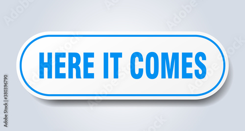 here it comes sign. rounded isolated button. white sticker