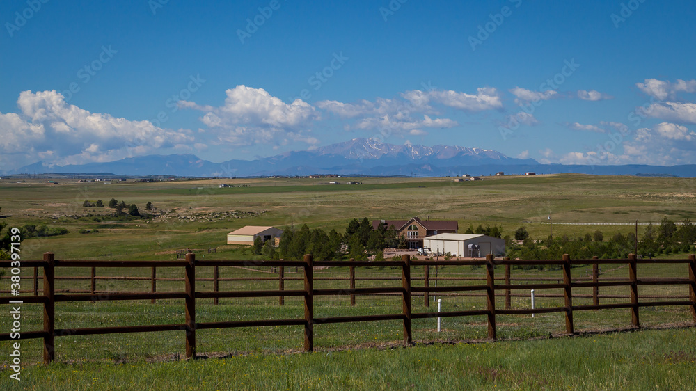 Ranch in Colorado with fence in foreground and mountains in the background