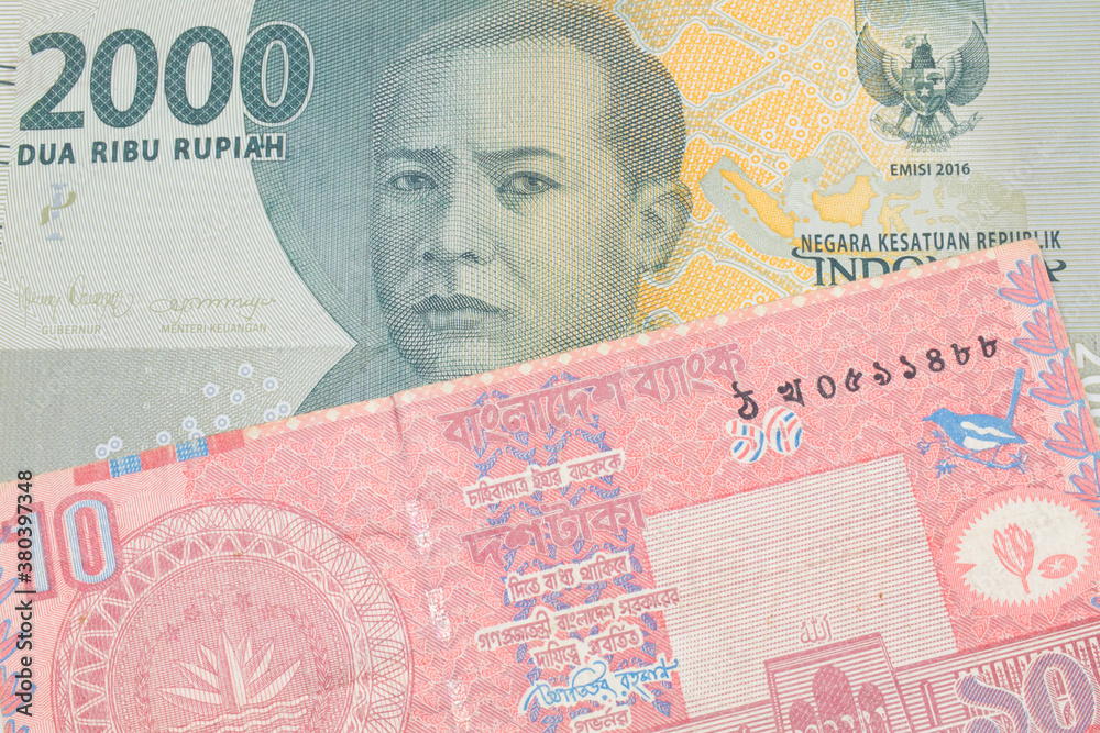 Fototapeta premium A macro image of a grey two thousand Indonesian rupiah bank note paired up with a red ten taka bank note from Bangladesh. Shot close up in macro.