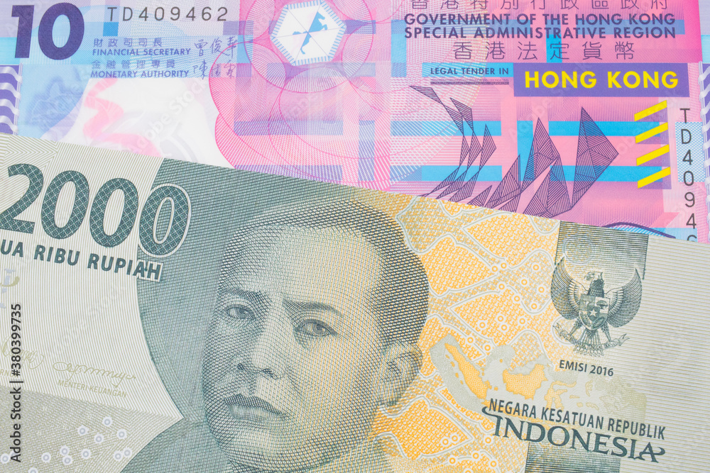 A macro image of a grey two thousand Indonesian rupiah bank note paired up with a pink and purple, plastic ten dollar bill from Hong Kong.  Shot close up in macro.