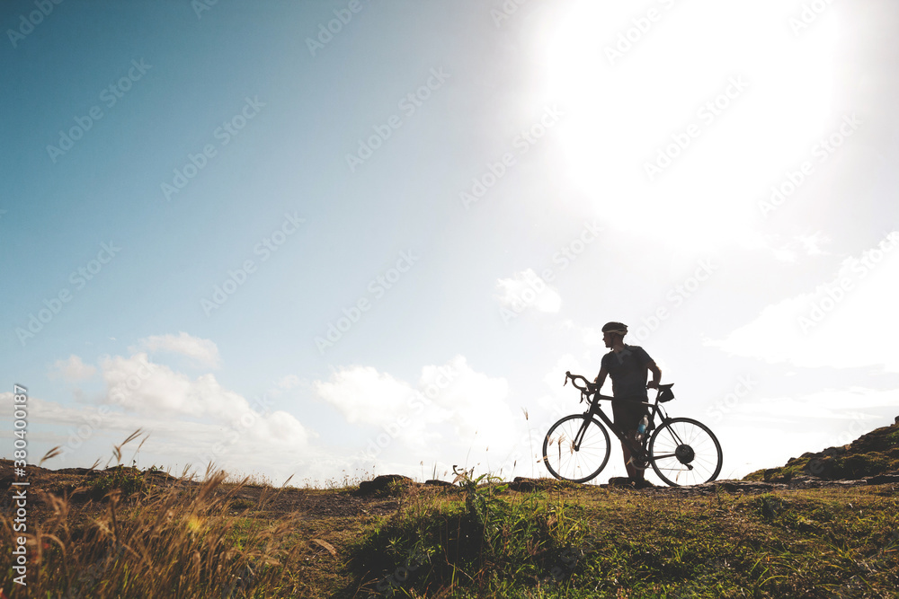 Silhoutte of young active cycle man standing near road - looking at view Silhoutte of young active cycle man standing near road - looking at view
