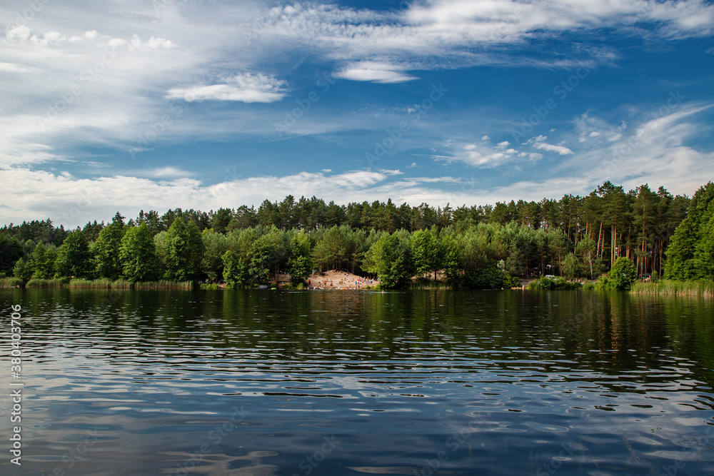 Beautiful lake in the woods with pine trees on the shore for summer vacation. Travel to Ukraine.