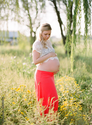 Pregnant woman walking through a field of yellow wildflowers photo