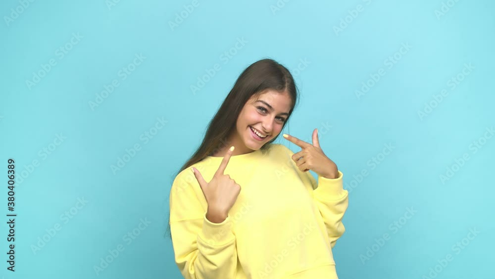 Young caucasian woman smiles, pointing fingers at mouth Young caucasian woman smiles, pointing fingers at mouth