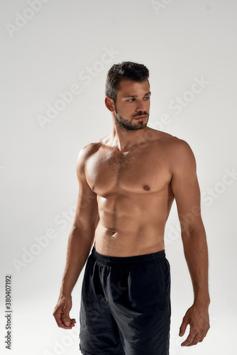 Vertical shot of a young handsome athletic caucasian man with beautiful naked torso posing shirtless isolated over grey background