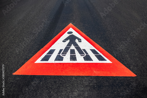 Close-up of pedestrian sign painted on asphalting road. © Lalandrew
