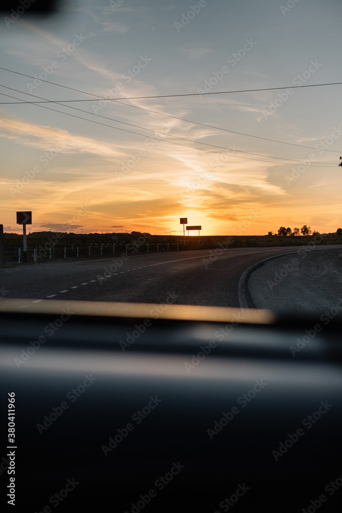 Beautiful sunset sky with tree silhouettes on the horizon, view from the car