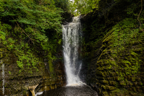 Tall waterfall in a narrow canyon surrounded by green foliage  Sgwd Einion Gam  Waterfall Country  Wales 