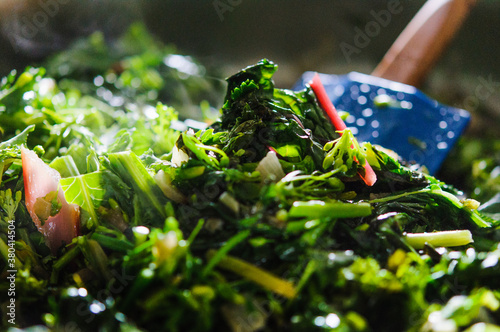 Kale raab, chard, and other spring greens being cooked and stirred photo