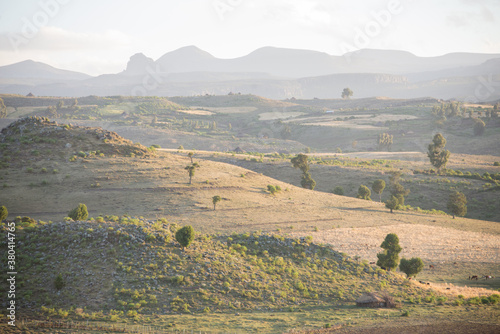 A backlit landscape shot with slight mist and rolling hills.