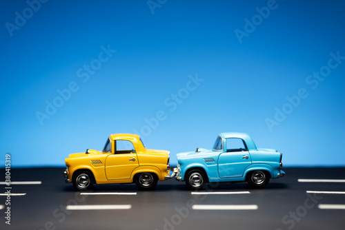 Two cars stand in a row on a road and a blue background. © ardasavasciogullari