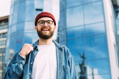 Fashionable portrait of young happy successful stylish bearded male hipster looking straight into the camera and smiling