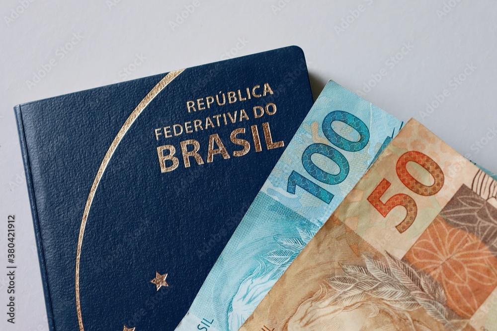 Obraz premium Brazilian Passport and Brazilian money on white background. Travel concept.